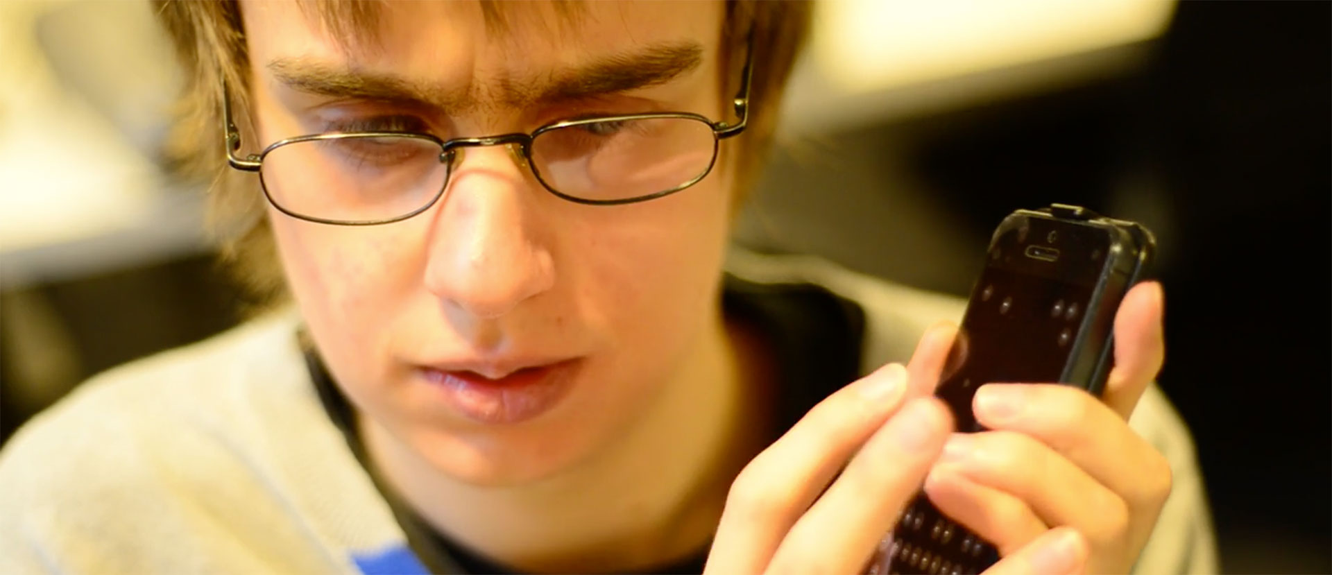 Een blinde jongeman die zijn telefoon bedient